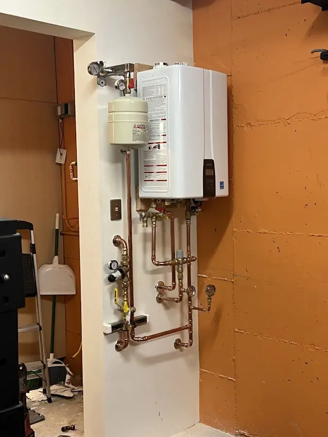 Plumbing technician inspecting water heater connections in Kaukauna